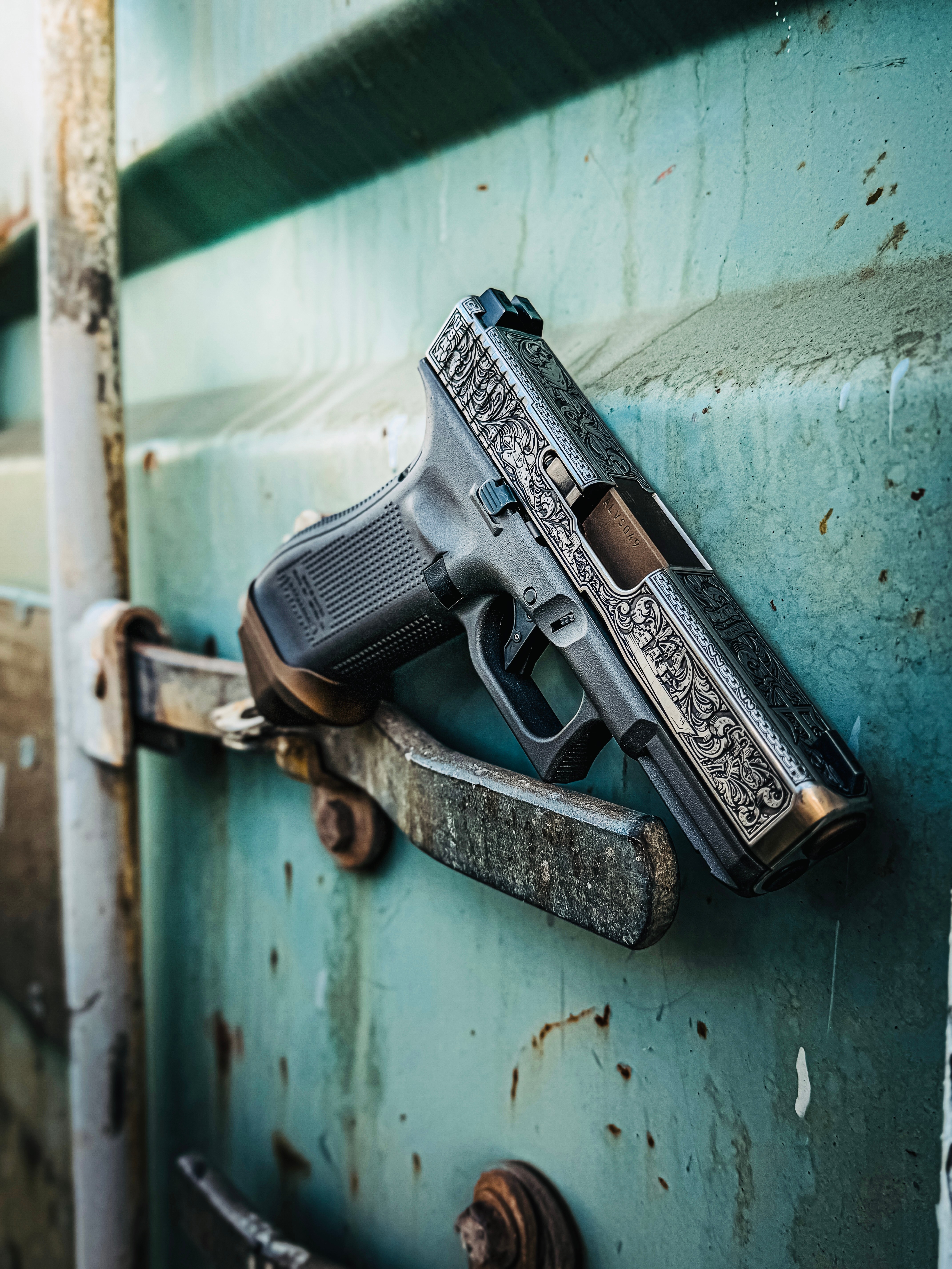 USNA Class of 2027 GLOCK 19X V — hanging on rusted teal door latch