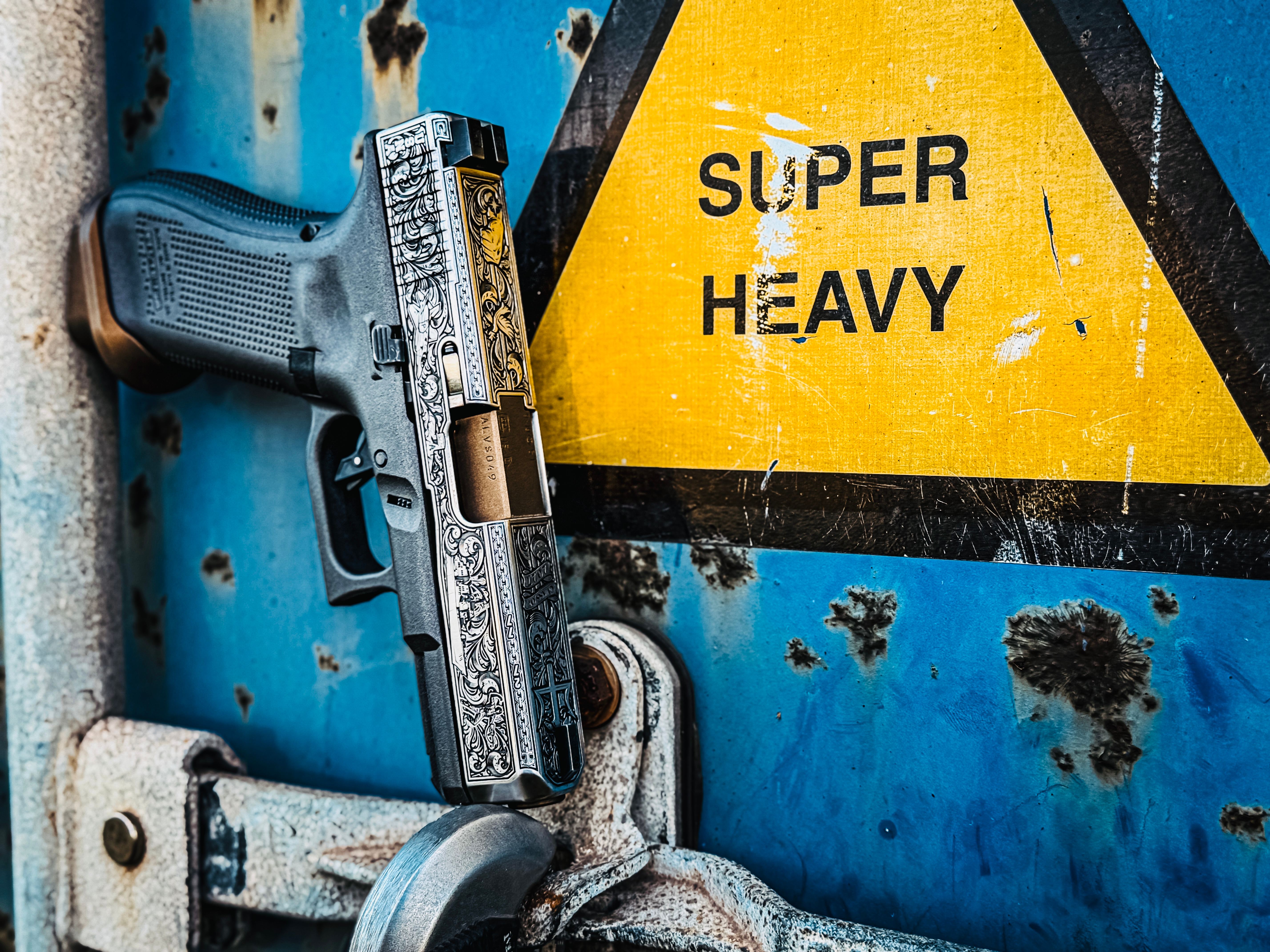 USNA Class of 2027 GLOCK 19X V — against a weathered “Super Heavy” warning sign