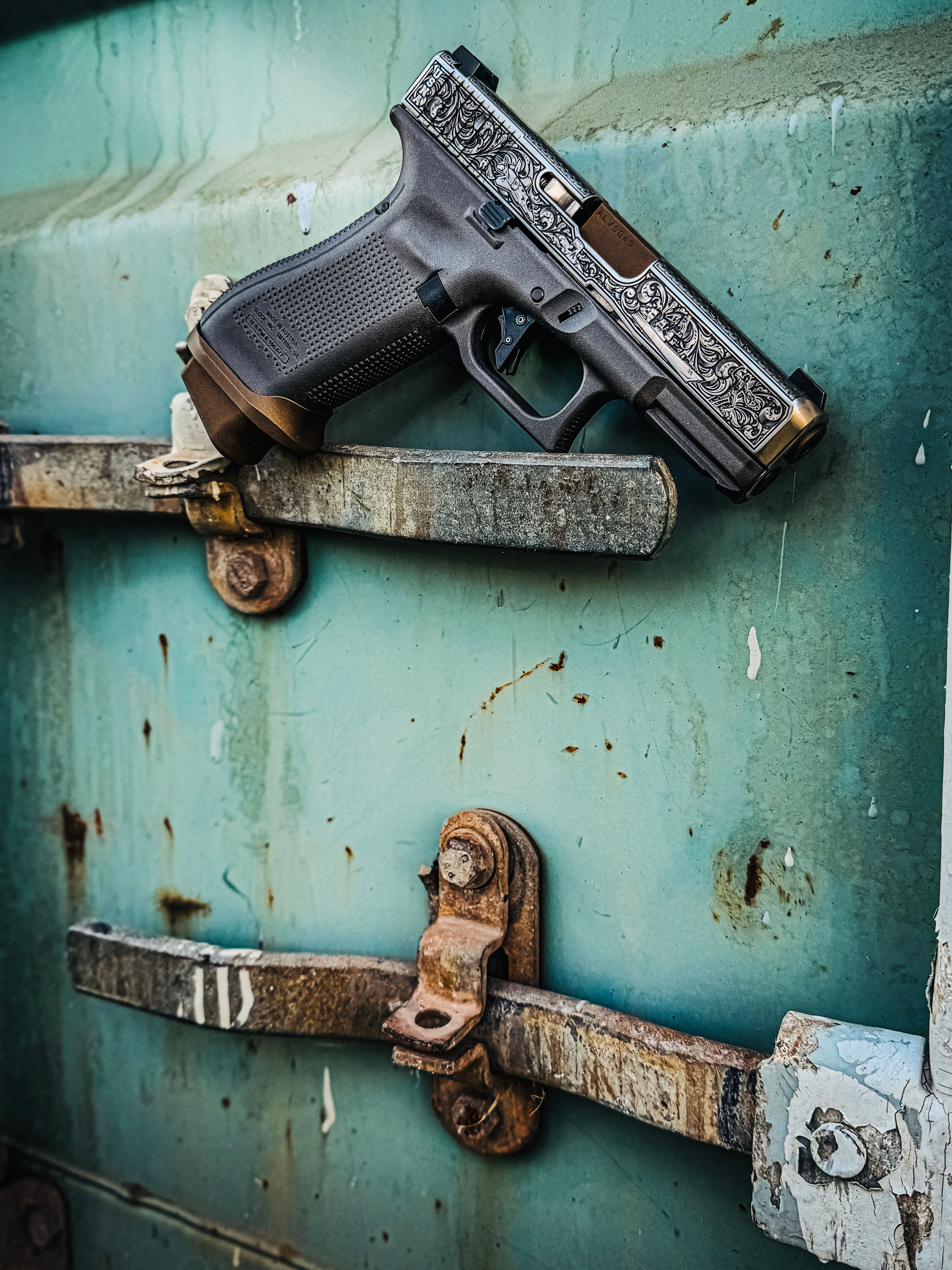 USNA Class of 2027 GLOCK 19X V — hanging on rusted latch, outdoor daylight