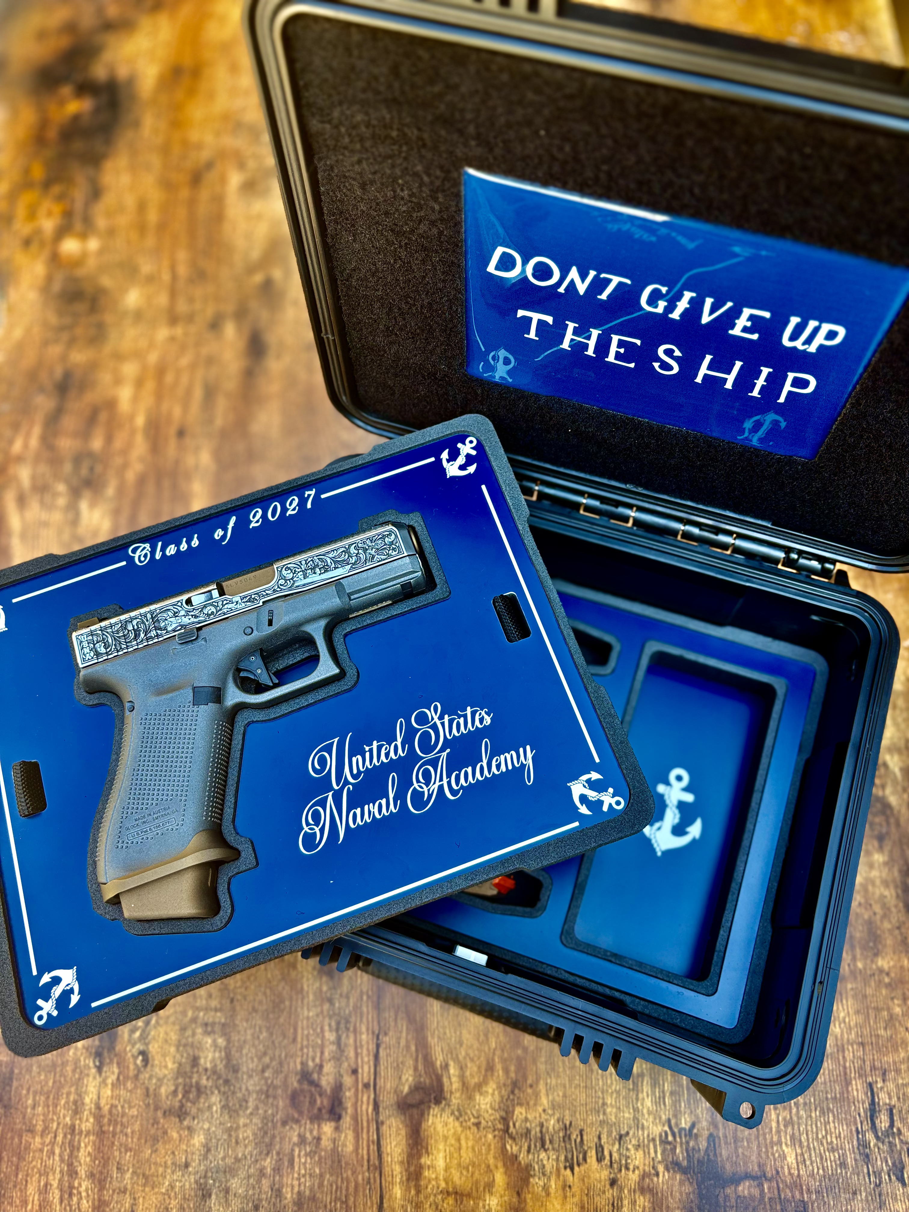 USNA Class of 2027 GLOCK 19X V — angled view of the open presentation case with the “Class of 2027, United States Naval Academy” pistol tray lifted beneath the “Don't Give Up the Ship” lid panel